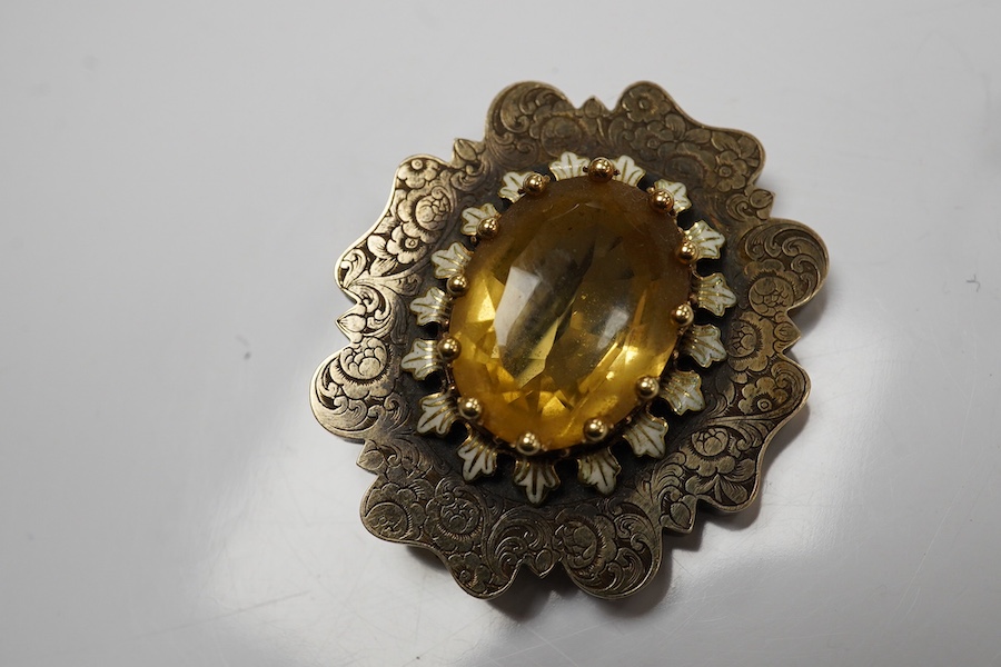 A citrine brooch and a paste and simulant pearl earring, 19th century, comprising: a brooch set with an oval citrine, within a lobed border engraved with floral designs, accented with white enamel, length 3.58cm; and a p